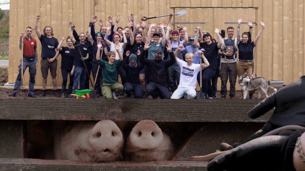 Community mit vielen Menschen vor dem Stall